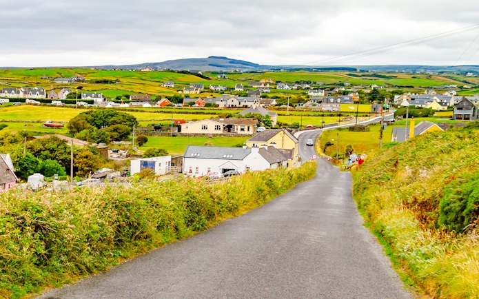 Doolin village road with houses and green fields in County Clare, Ireland.