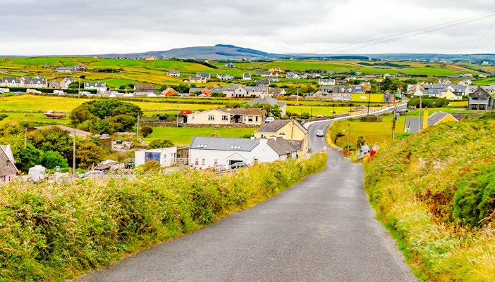 Doolin village road with houses and green fields in County Clare, Ireland.