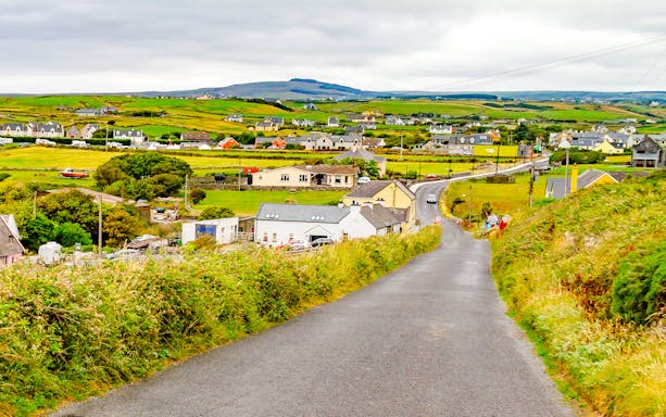Doolin village road with houses and green fields in County Clare, Ireland.