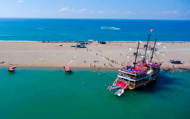 Cruise ship docked on sandy beach during Side Manavgat River Cruise tour.