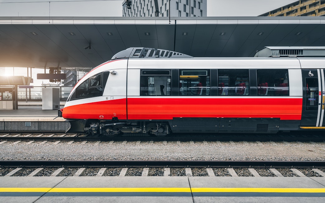 Modern red and white train at a city train station platform.