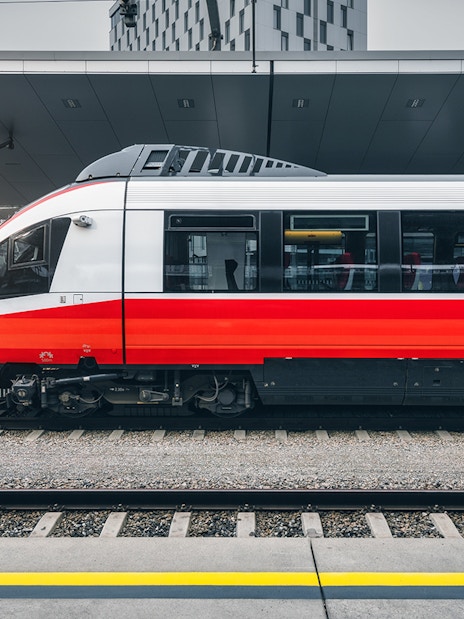 Modern red and white train at a city train station platform.