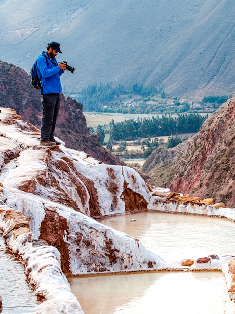 Tourists exploring Maras Salt Mines terraces in Sacred Valley, near Cusco, Peru.