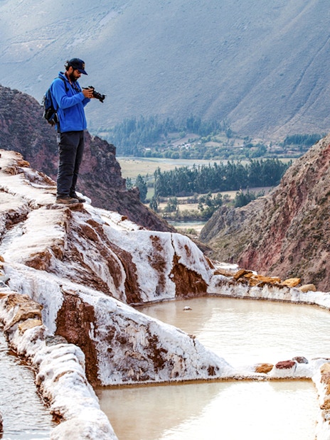Tourists exploring Maras Salt Mines terraces in Sacred Valley, near Cusco, Peru.