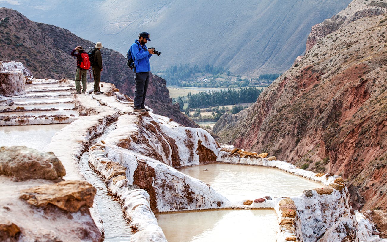 Tourists exploring Maras Salt Mines terraces in Sacred Valley, near Cusco, Peru.