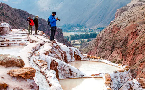 Tourists exploring Maras Salt Mines terraces in Sacred Valley, near Cusco, Peru.