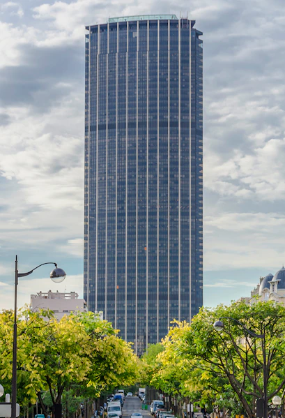 Montparnasse Tower in Paris with tree-lined street in foreground.