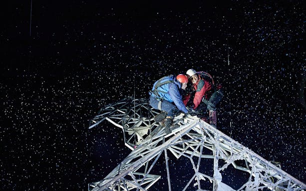 Climbers on a snowy metal structure at night, Touching The Void experience.