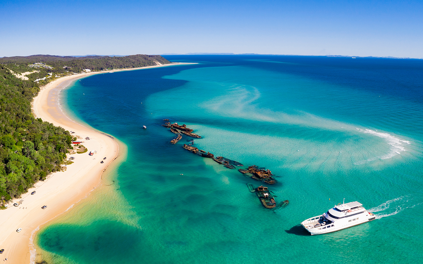 Shipwrecks and a boat near the shore of Moreton Island, Australia.