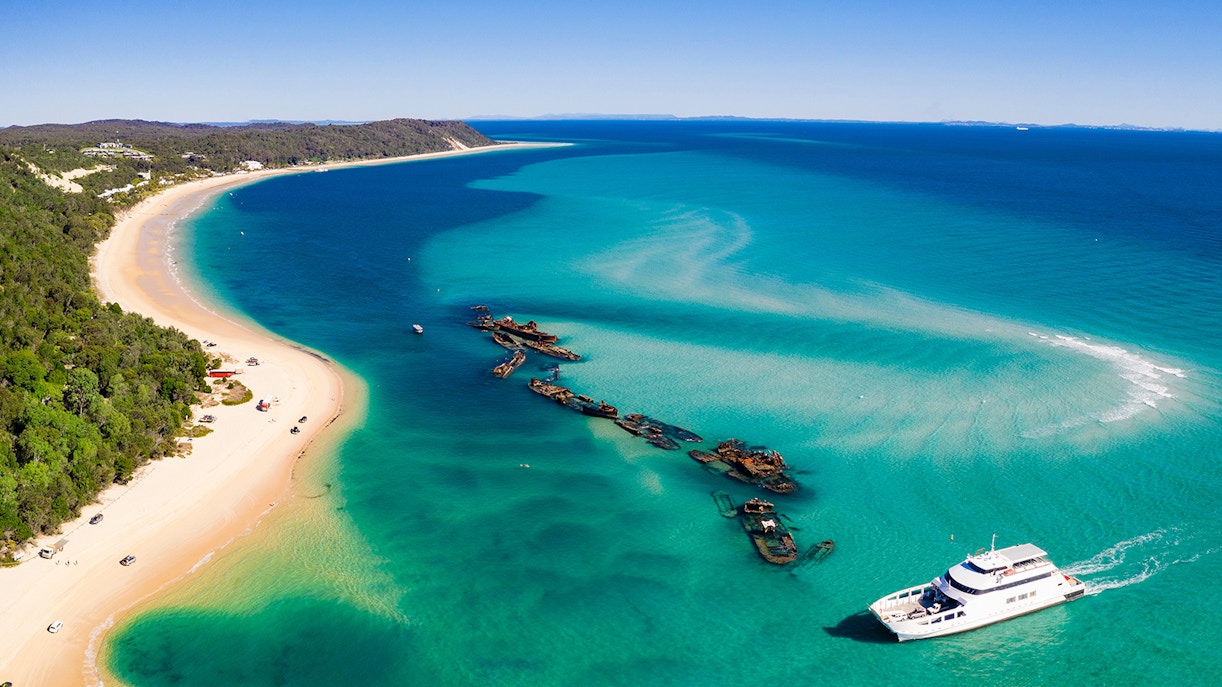 Shipwrecks and a boat near the shore of Moreton Island, Australia.