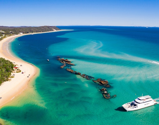 Shipwrecks and a boat near the shore of Moreton Island, Australia.