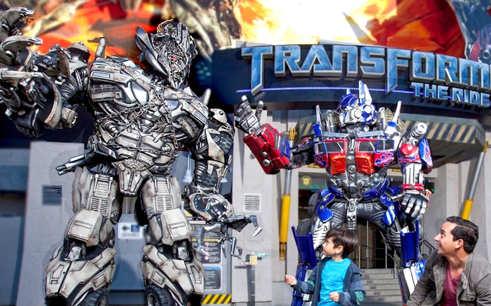 Transformers characters at Universal Studios Hollywood with visitors in front of the ride entrance.
