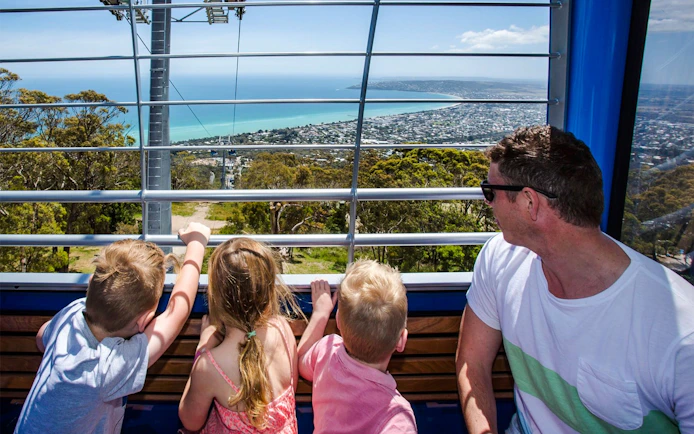 Family enjoying the view from Arthurs Seat Eagle gondola, overlooking the coastline.