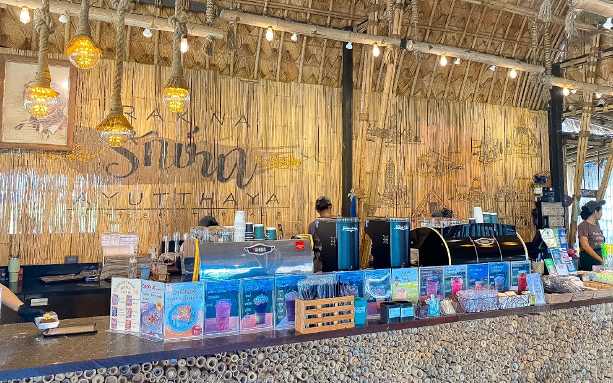 Cafe Rakna coffee counter with bamboo decor and menu displays in Ayutthaya.
