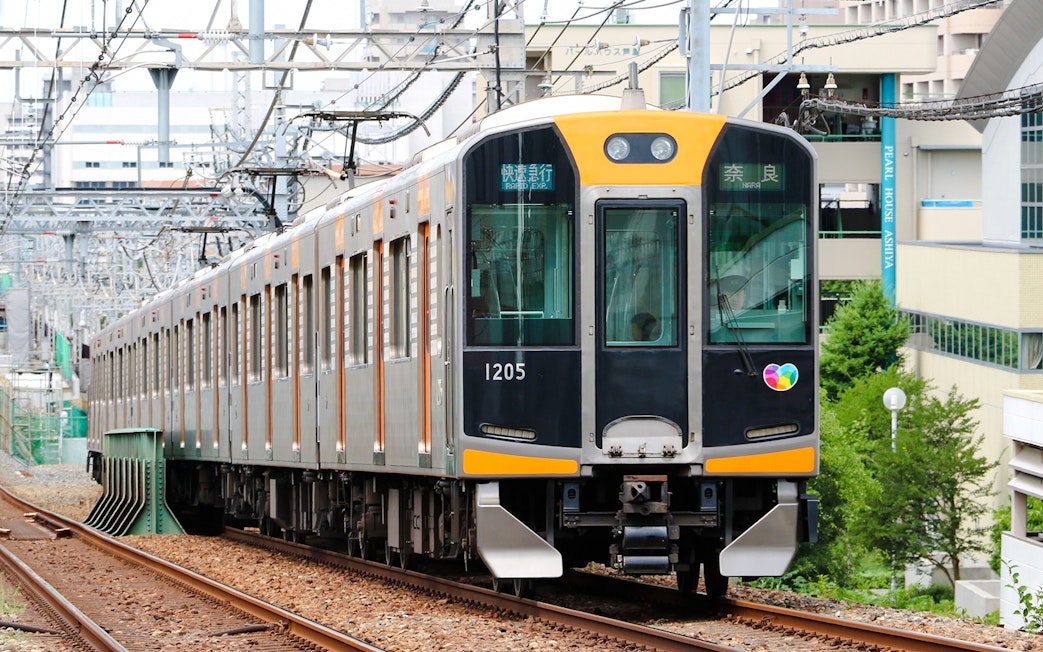 Kansai Railway train traveling on urban tracks in Japan.
