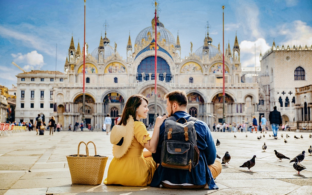 Couple sitting in front of St. Mark's Basilica, Venice, during guided tour with priority entry.