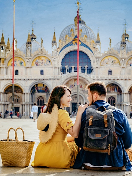 Couple sitting in front of St. Mark's Basilica, Venice, during guided tour with priority entry.