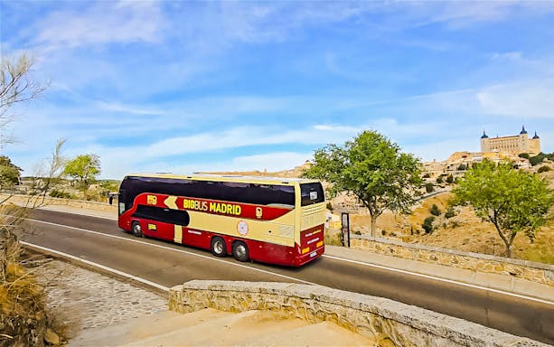 Big bus traveling from Madrid to Toledo with Alcázar in the background.