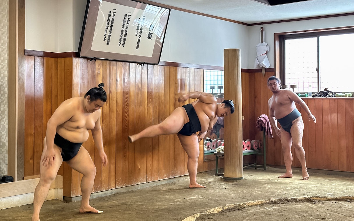 Sumo wrestlers practicing morning exercises in a traditional Japanese sumo stable.