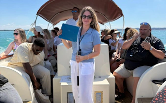 Guide leading a boat tour on Lake Garda with passengers seated.