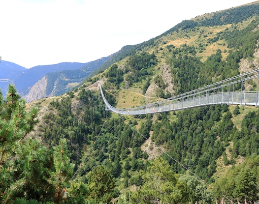 Tibetan Bridge in Andorra spanning a lush green valley with mountain views.