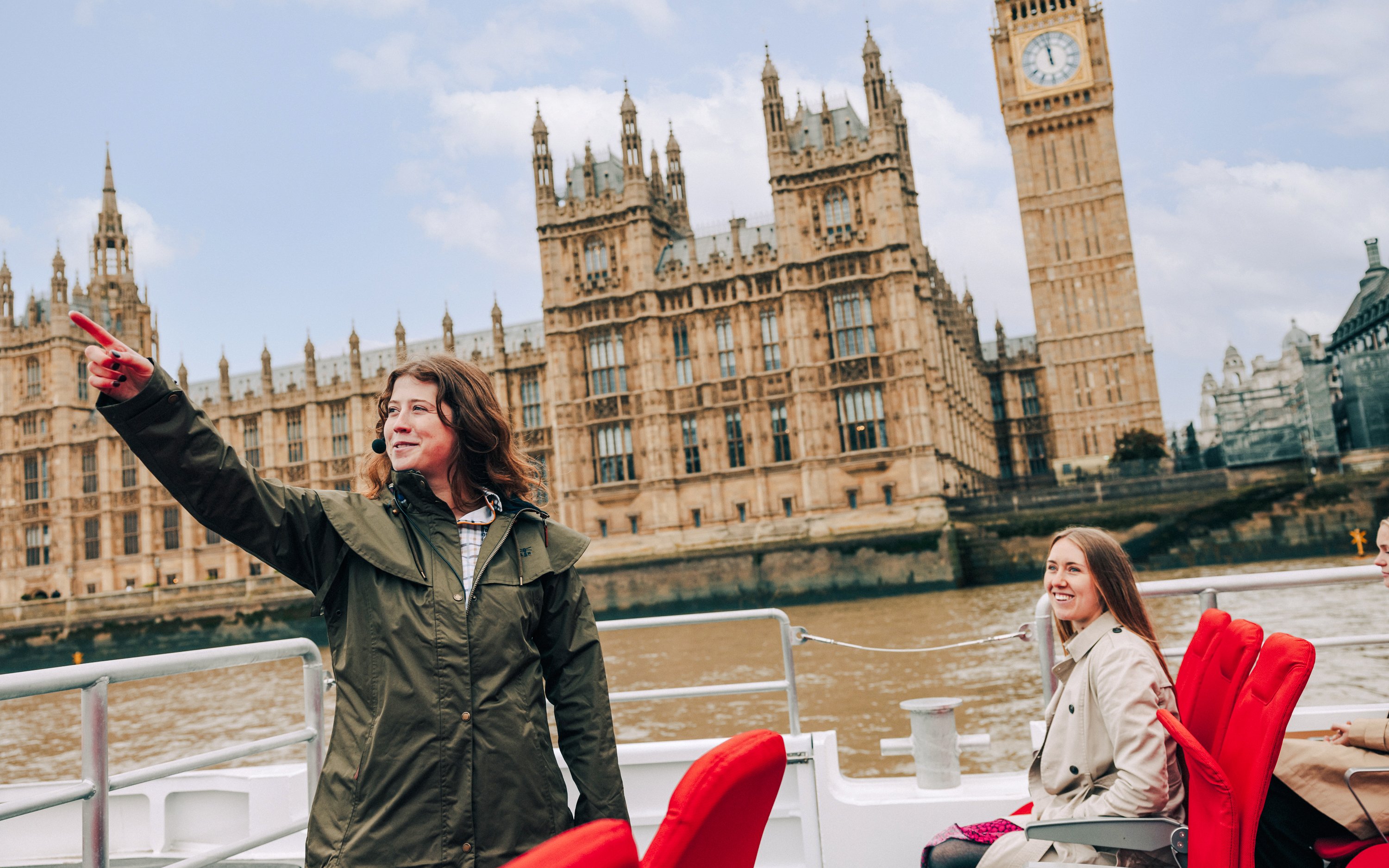 Guests and guide on Tower of London Cruise boat with Houses of Parliament in background.