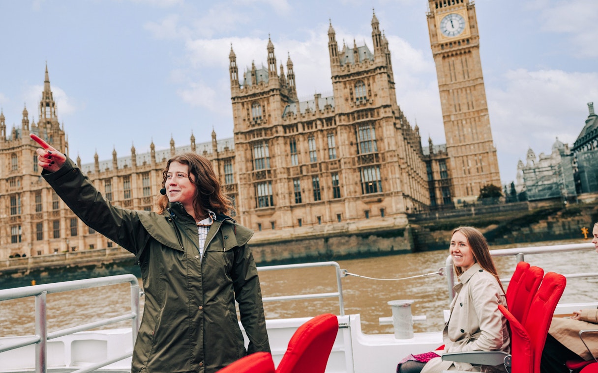 Guests and guide on Tower of London Cruise boat with Houses of Parliament in background.