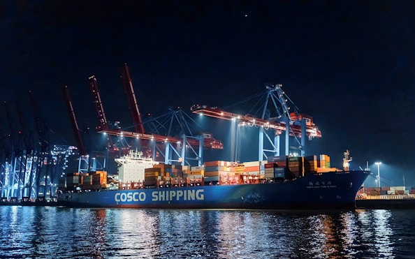 Large ship docked at night with illuminated cranes, part of the 1.5h Grand Evening Lights Cruise.