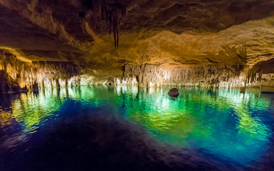 Drach Caves illuminated stalactites reflecting in turquoise water, Mallorca.
