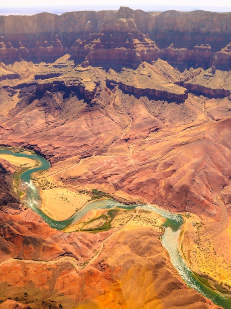Aerial view of the Grand Canyon with winding Colorado River and layered rock formations.