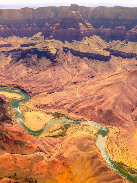 Aerial view of the Grand Canyon with winding Colorado River and layered rock formations.