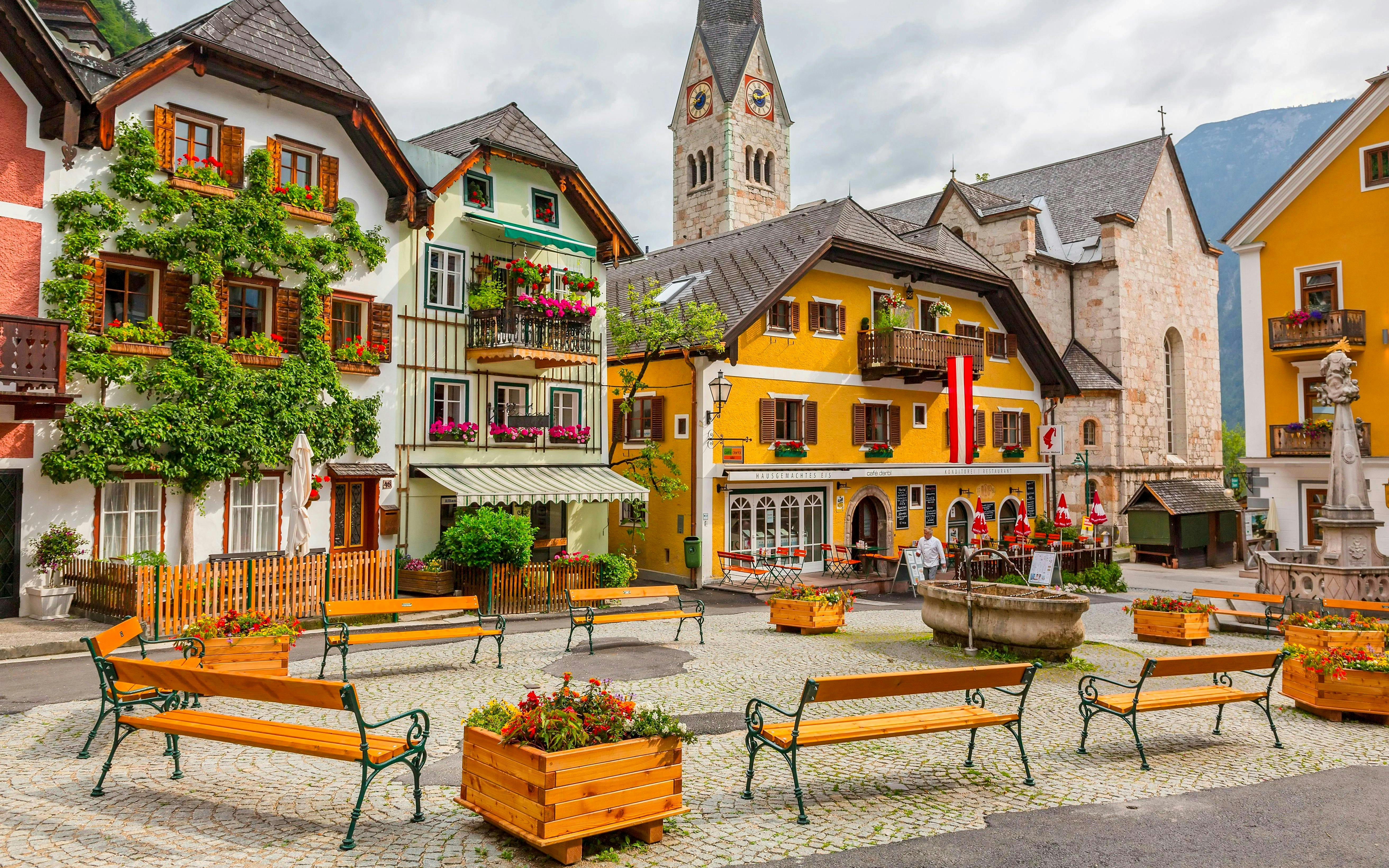 Old town square with colorful buildings and church tower in Hallstatt, Austria.