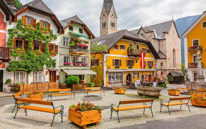 Old town square with colorful buildings and church tower in Hallstatt, Austria.