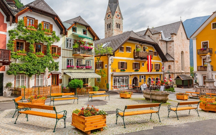 Old town square with colorful buildings and church tower in Hallstatt, Austria.