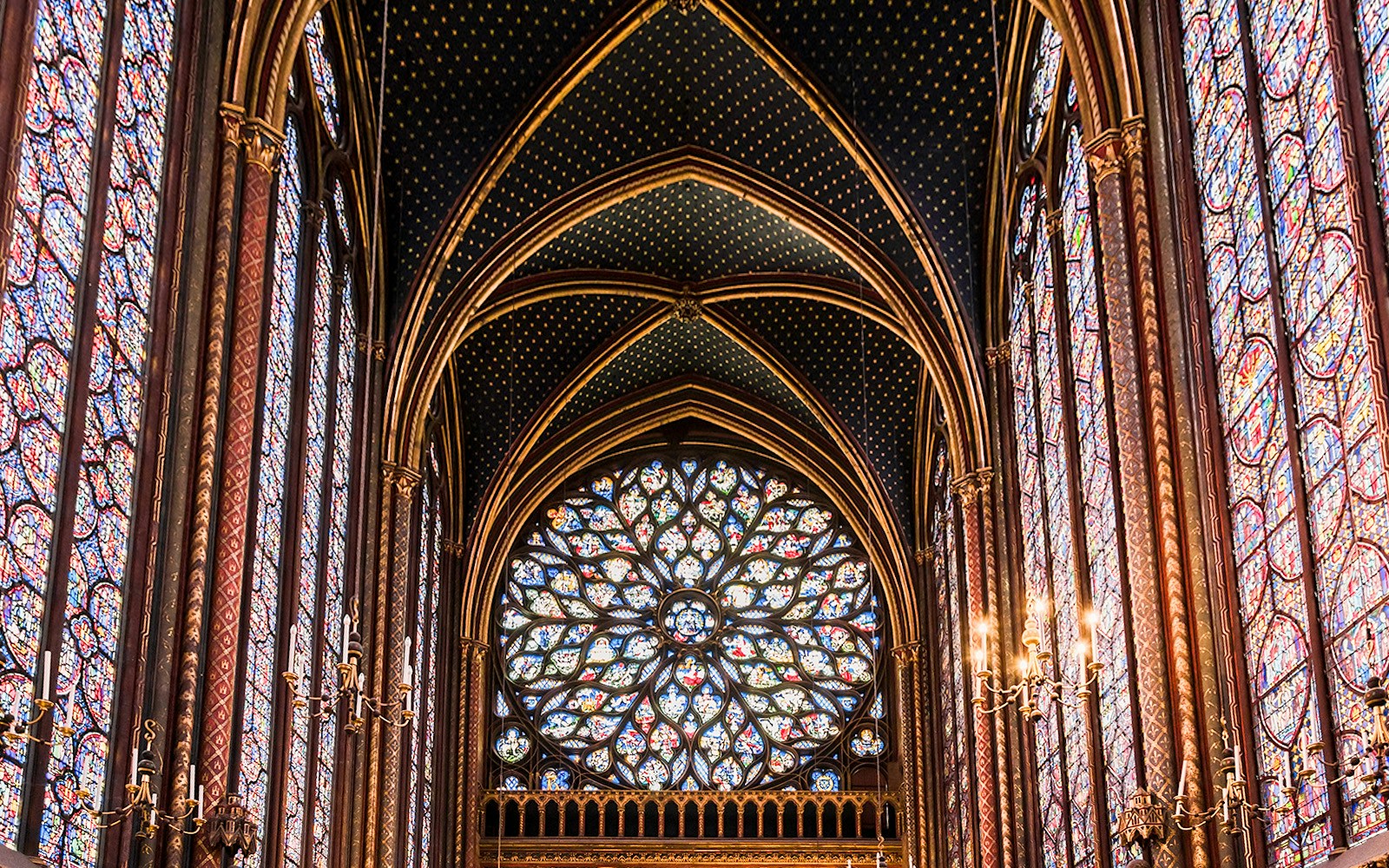 Stained rose glass window inside Sainte Chapelle, Paris, showcasing biblical scenes.