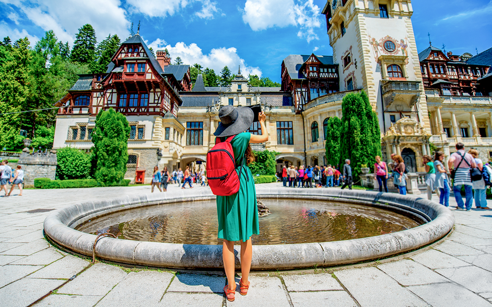 Tourist photographing Peleș Castle courtyard in Sinaia, Romania.