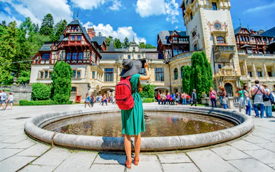 Tourist photographing Peleș Castle courtyard in Sinaia, Romania.