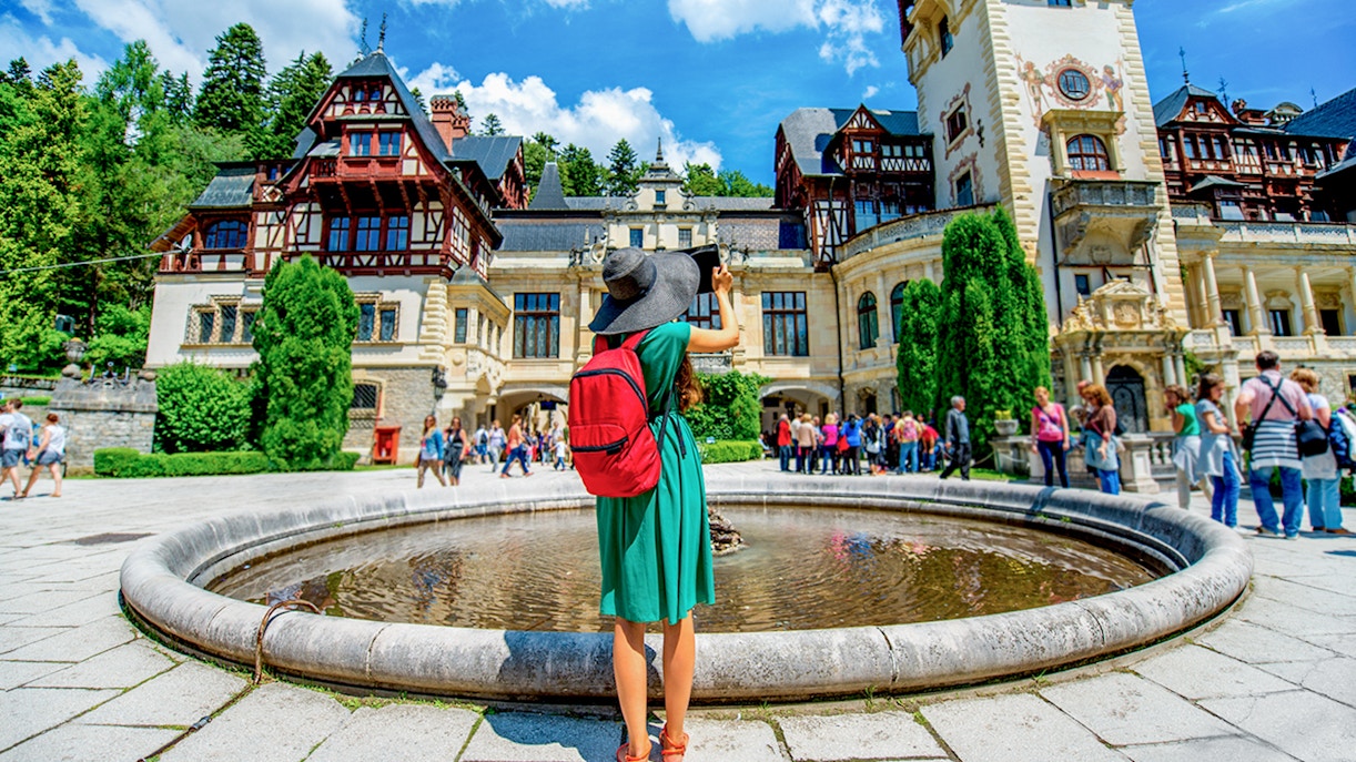 Tourist photographing Peleș Castle courtyard in Sinaia, Romania.