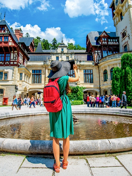Tourist photographing Peleș Castle courtyard in Sinaia, Romania.