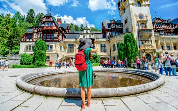 Tourist photographing Peleș Castle courtyard in Sinaia, Romania.