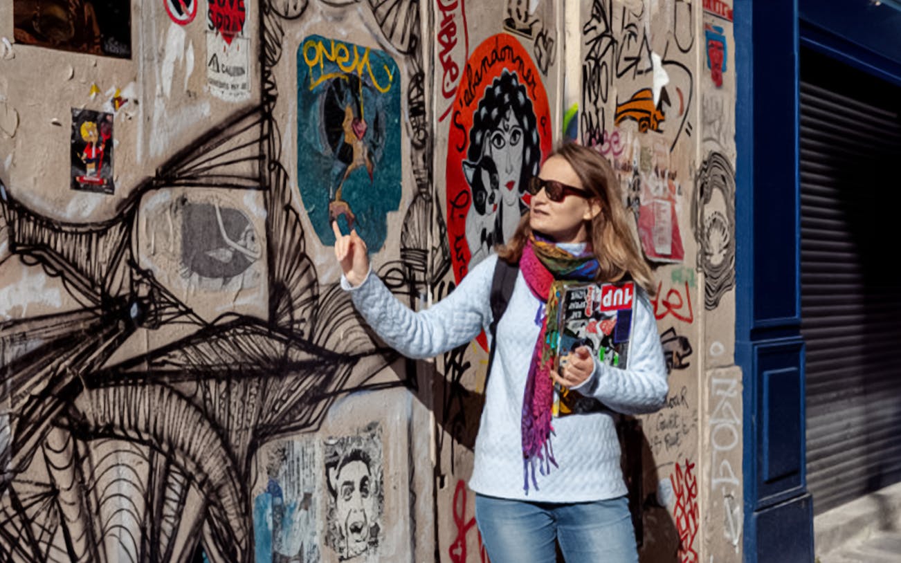 Montmartre street artist explaining wall art in Paris.