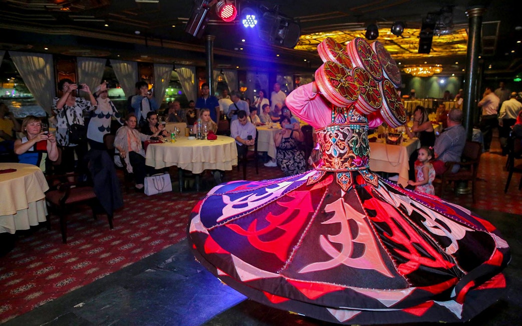 Dancer performing on a luxury Nile dinner cruise with an audience watching.