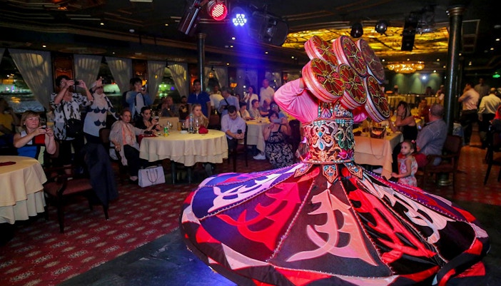 Dancer performing on a luxury Nile dinner cruise with an audience watching.