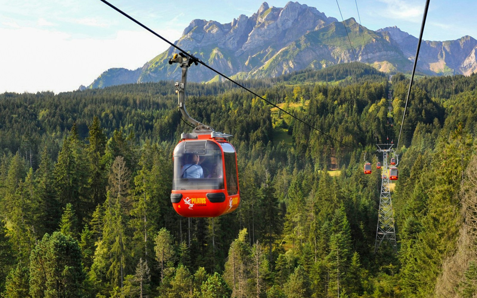 Cable car ascending Mount Pilatus with forest and mountain backdrop, Lucerne.