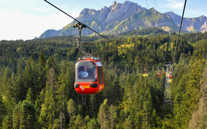 Cable car ascending Mount Pilatus with forest and mountain backdrop, Lucerne.