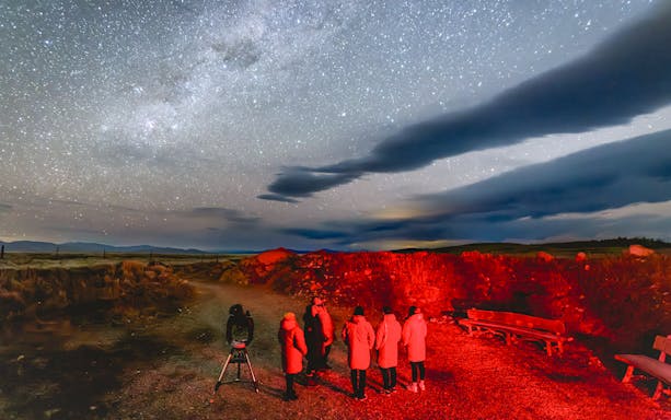 Tourists stargazing at The Crater under a starry sky with telescope.