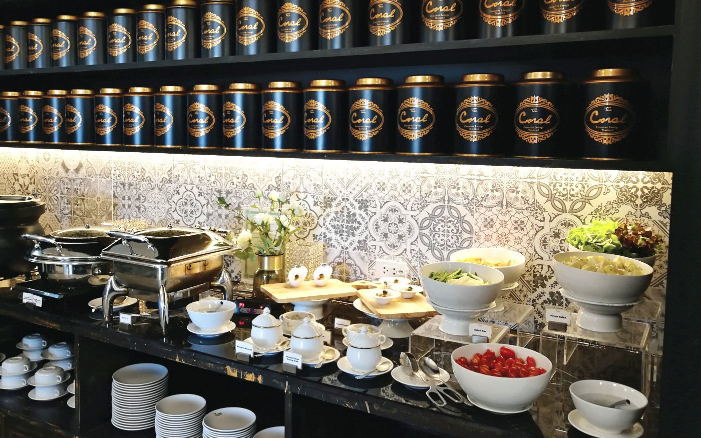 Buffet spread at The Coral Executive Lounge, Phuket International Airport, featuring salads and tea canisters.