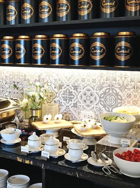Buffet spread at The Coral Executive Lounge, Phuket International Airport, featuring salads and tea canisters.