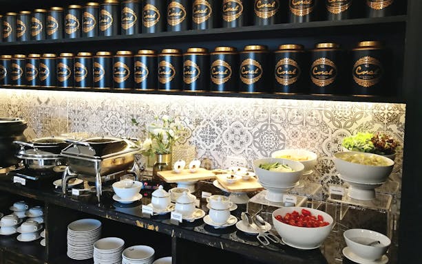 Buffet spread at The Coral Executive Lounge, Phuket International Airport, featuring salads and tea canisters.