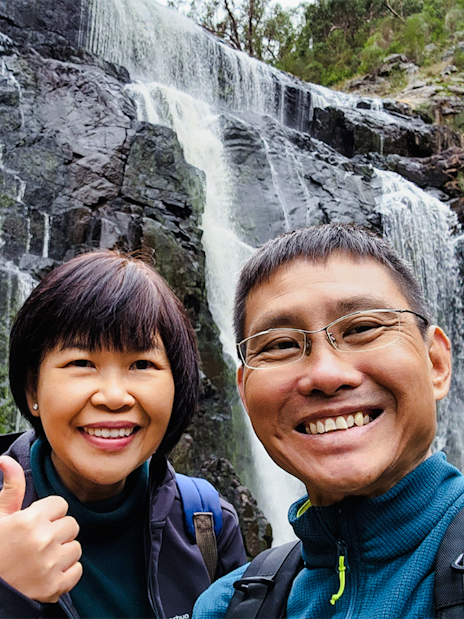 Visitors smiling in front of MacKenzie Falls, Grampians National Park.